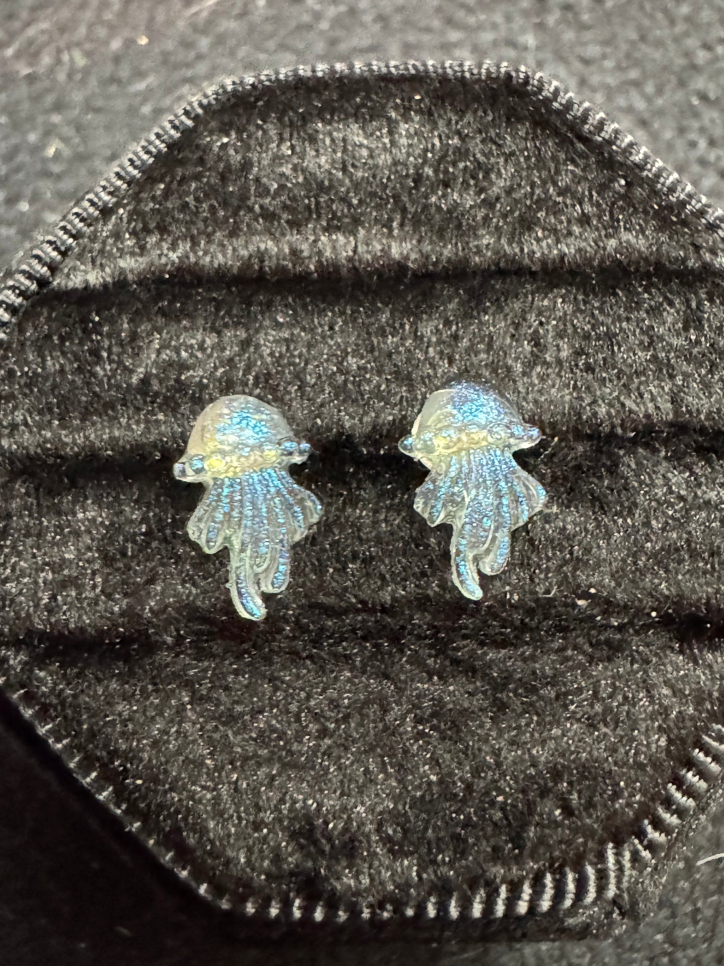 Pair of fish-shaped earrings on a textured black surface