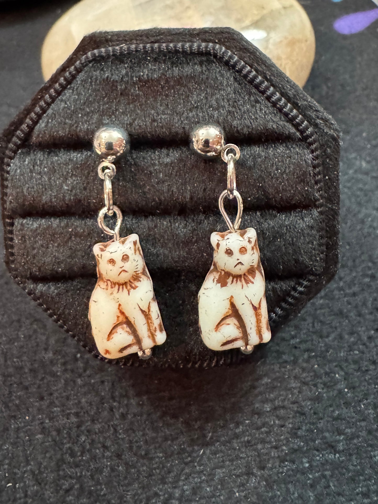 Cat-shaped earrings with bells on a black jewelry display