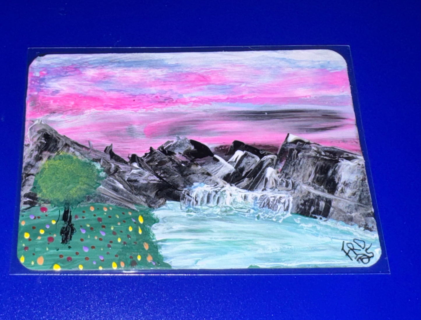 Artistic depiction of mountains and a tree with a colorful sky on a blue background