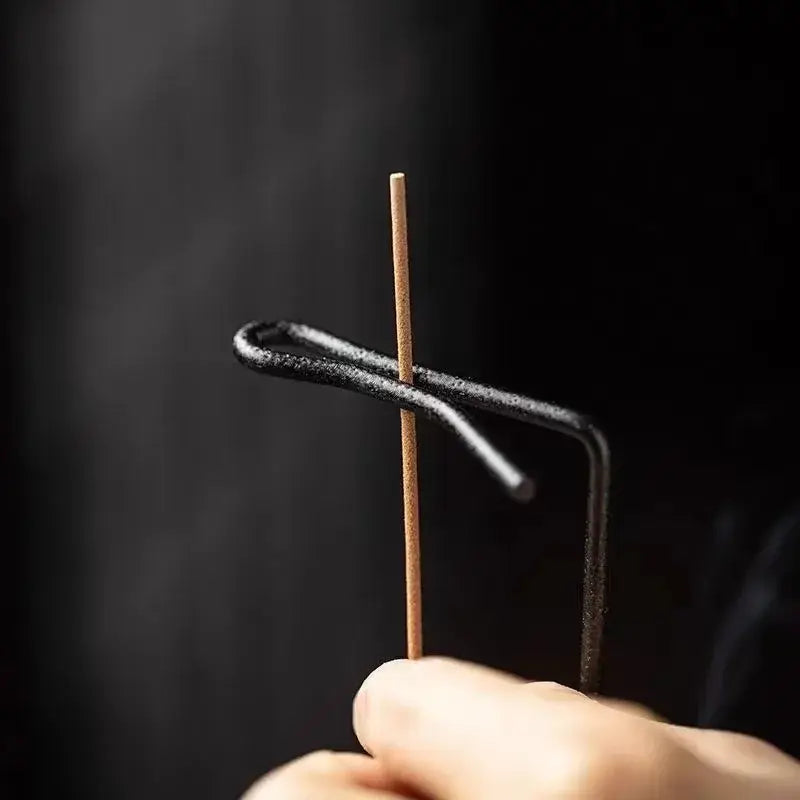 Hand holding a incense against a dark background
