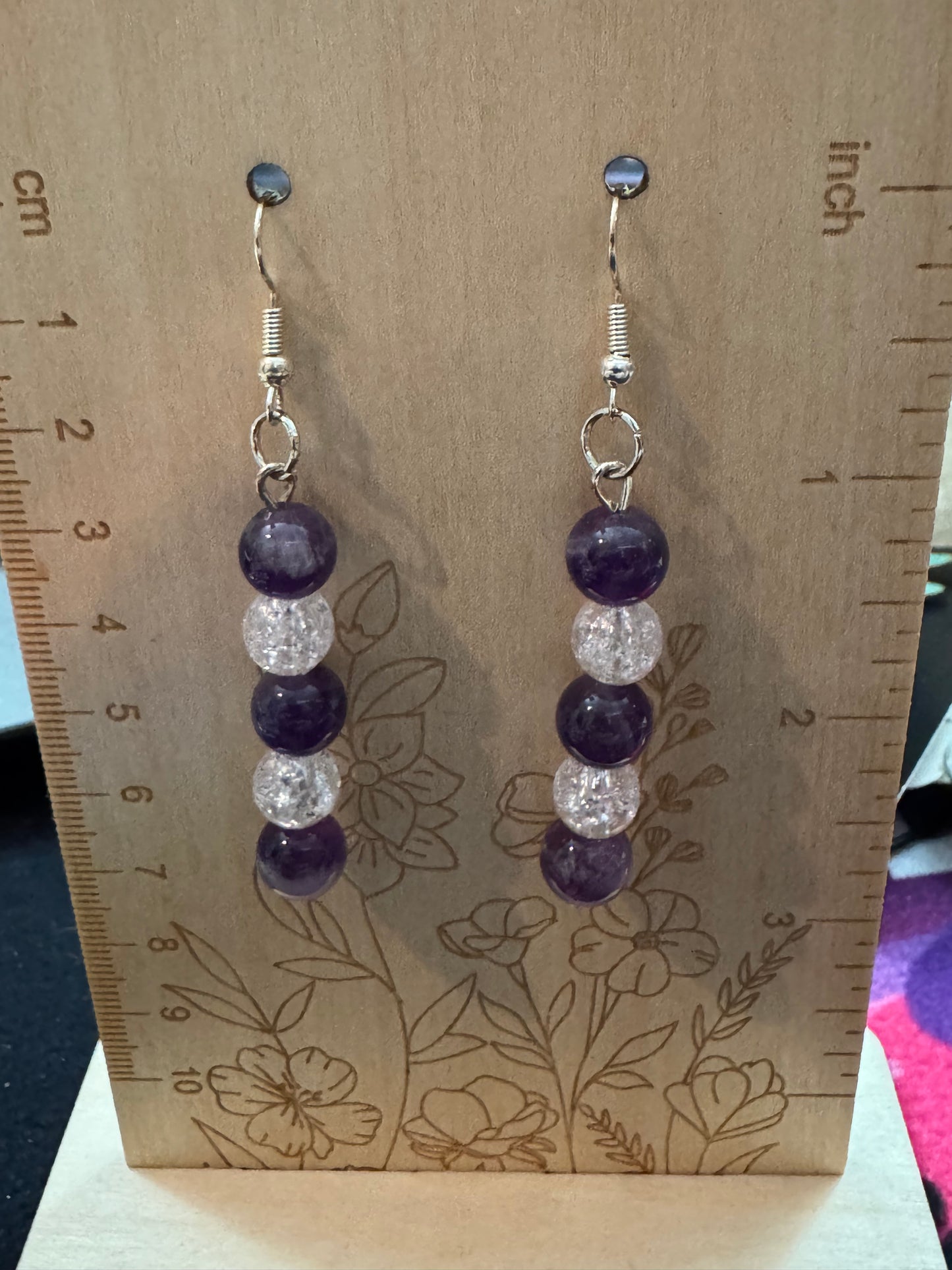 Pair of beaded earrings on a wooden surface with a ruler for scale.