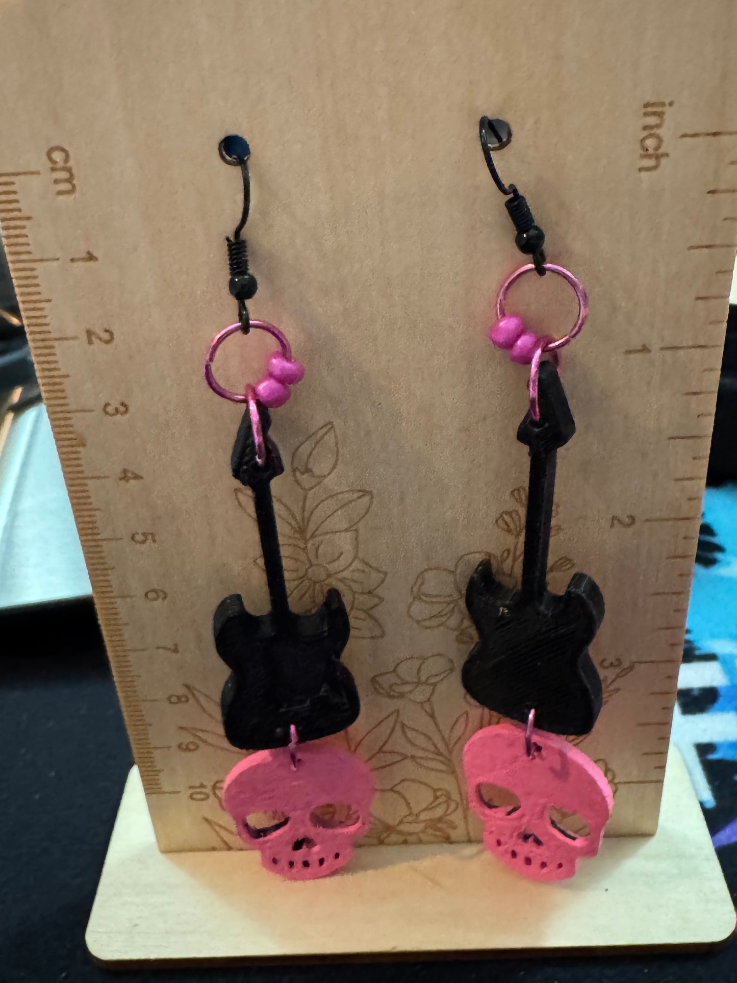 Black and pink earrings on a wooden board with a ruler for scale.