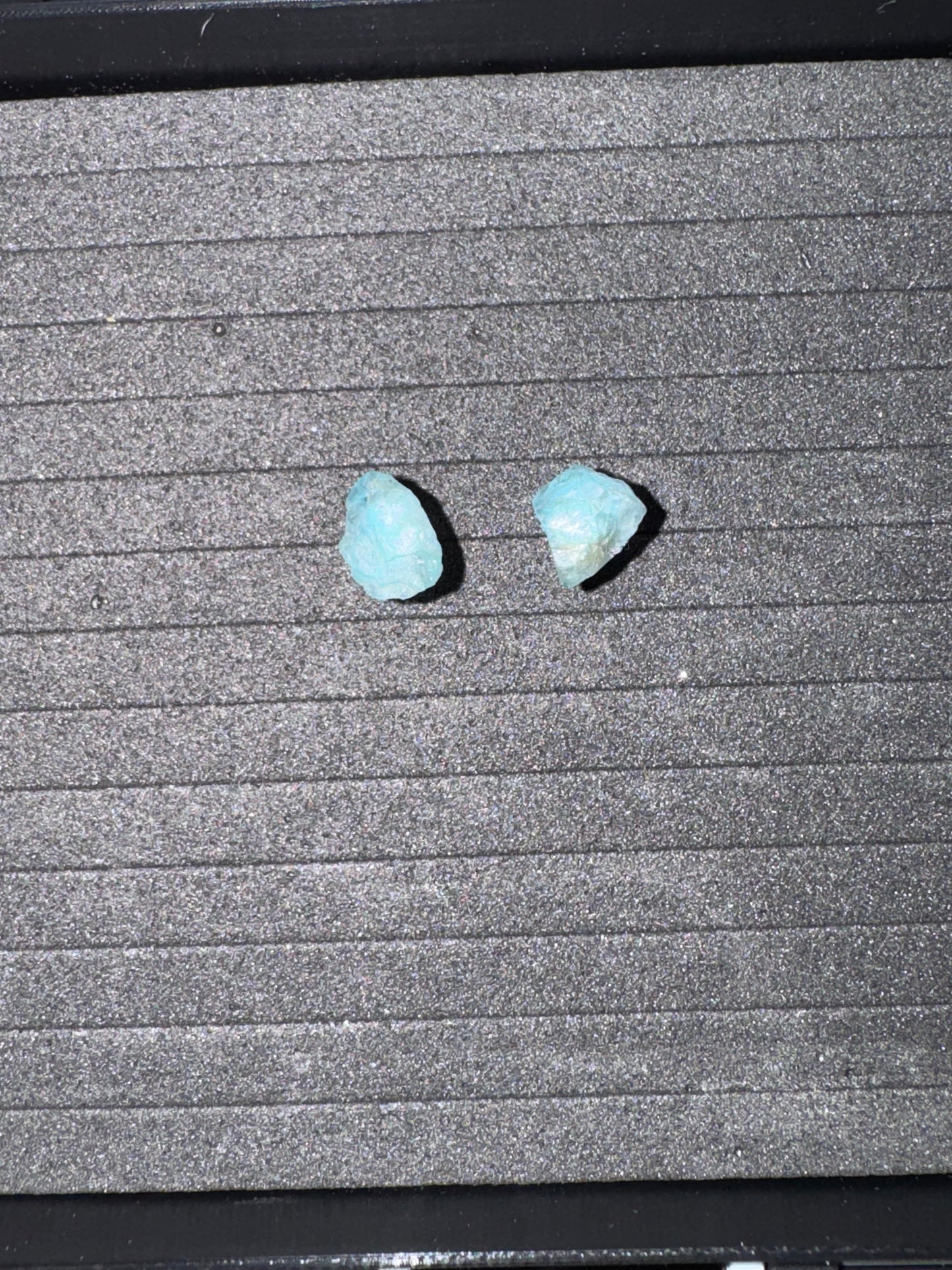 Two blue stones on a textured gray surface