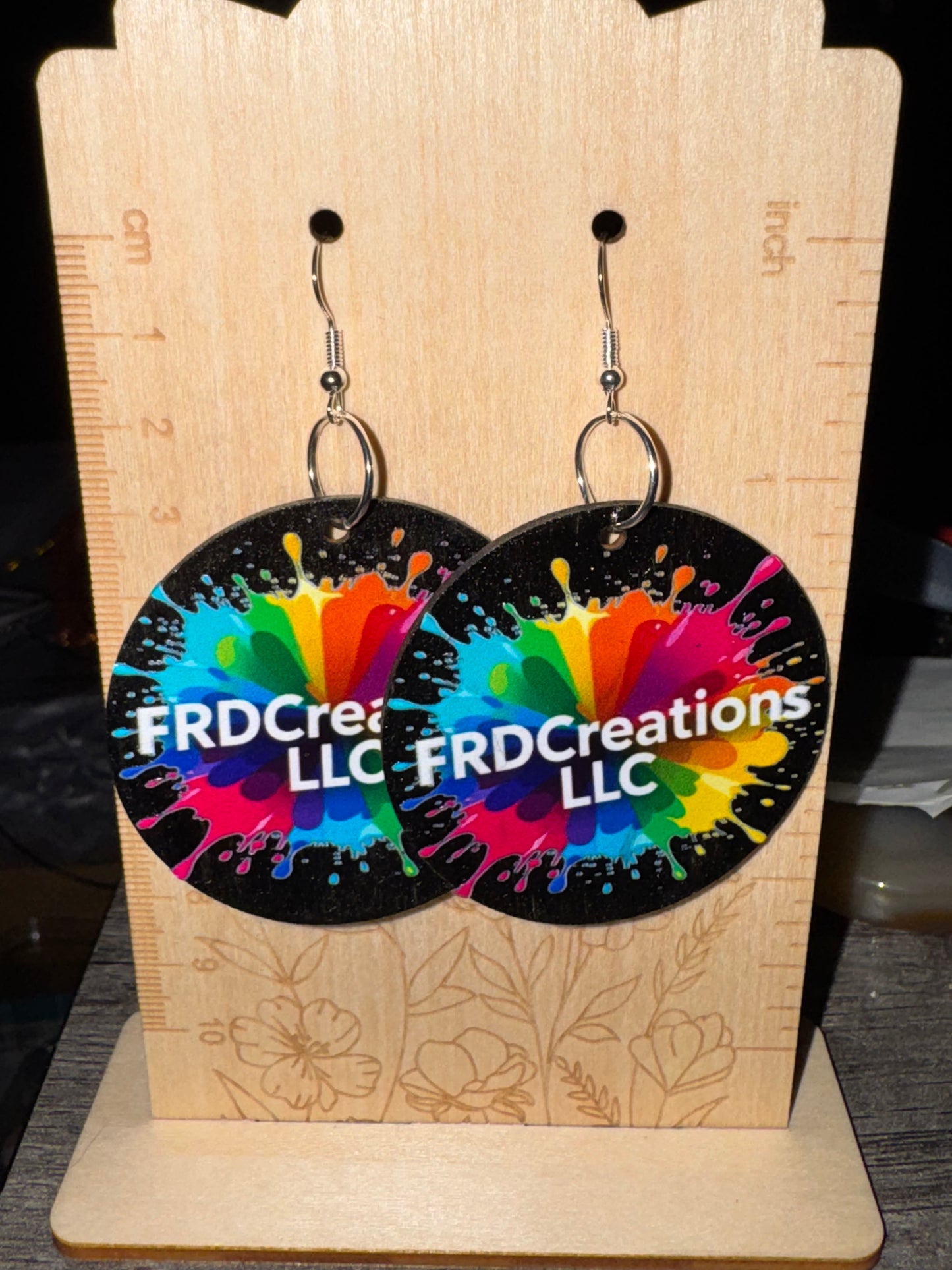 Colorful earrings with 'FRDCreations LLC' branding on a wooden display card.