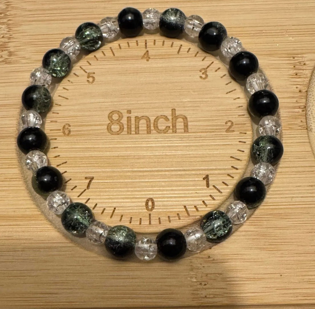 Green and Clear Beaded bracelet on a wooden ruler showing its length.