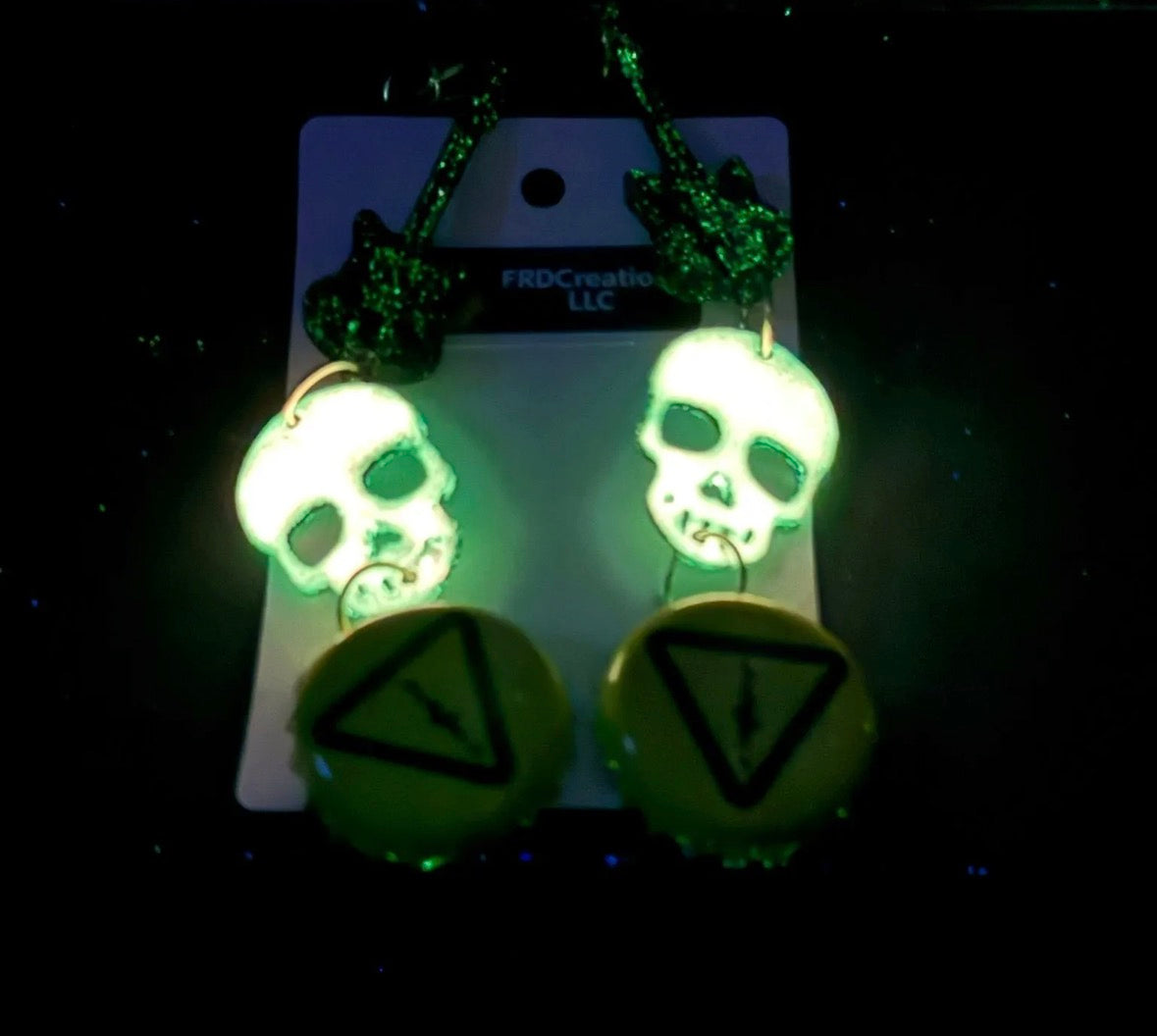 Glowing skull-shaped earrings on a dark background w