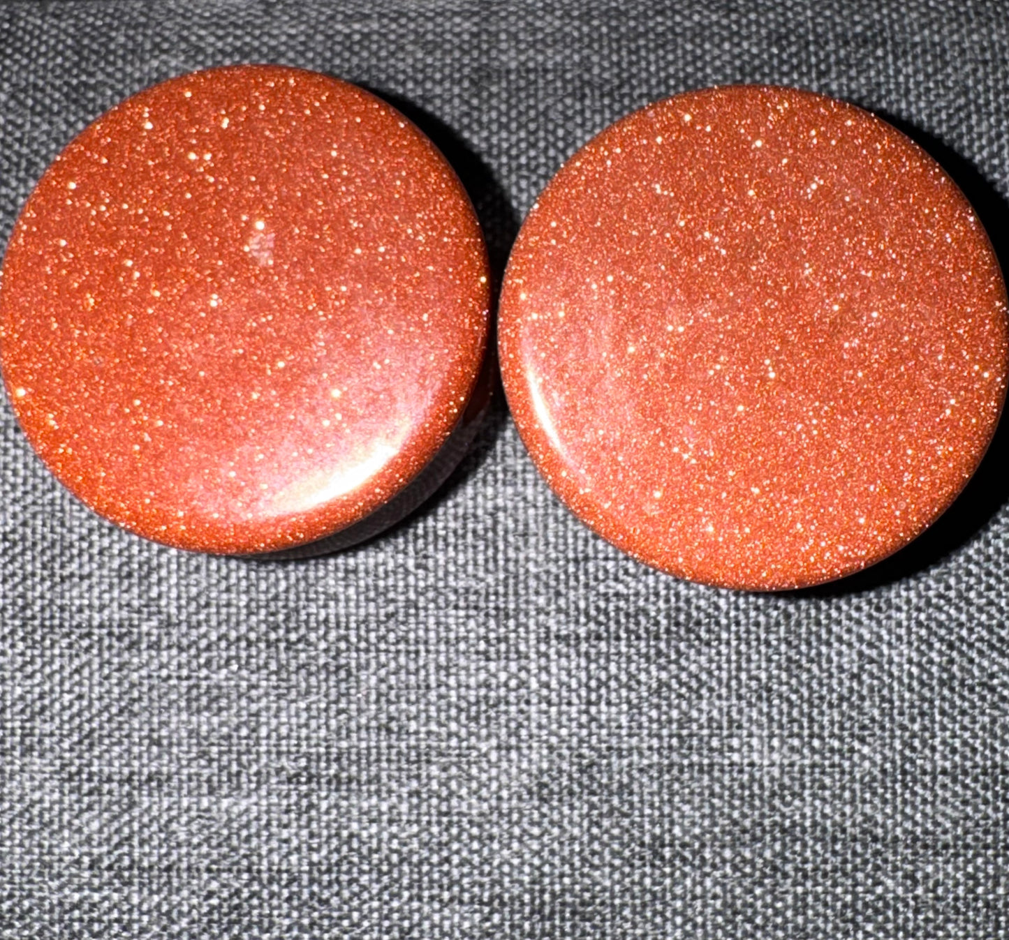 Two red stone gauges on a textured gray background