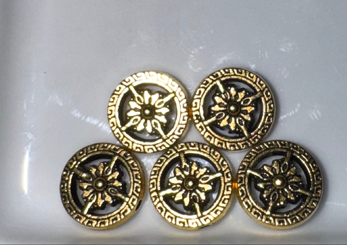 Five round decorative beads with an antique gold finish and a sunburst motif, arranged on a plain white surface.