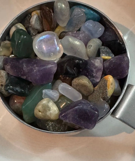 Colorful gemstones in a metal scoop on a light background