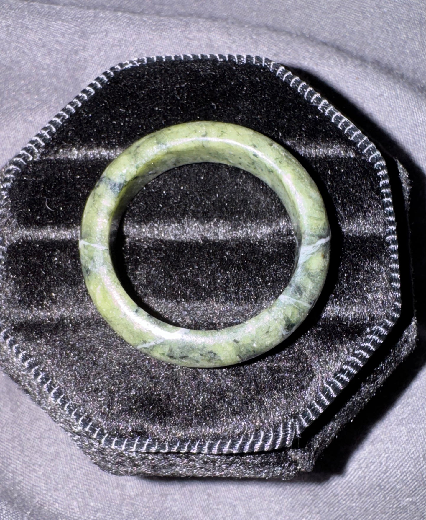 Green jade ring on a textured black and gray surface