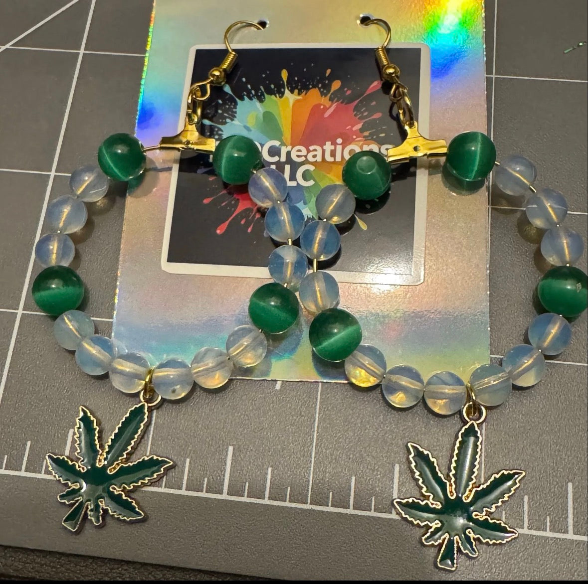 Earrings with cannabis leaf pendants on colorful card.