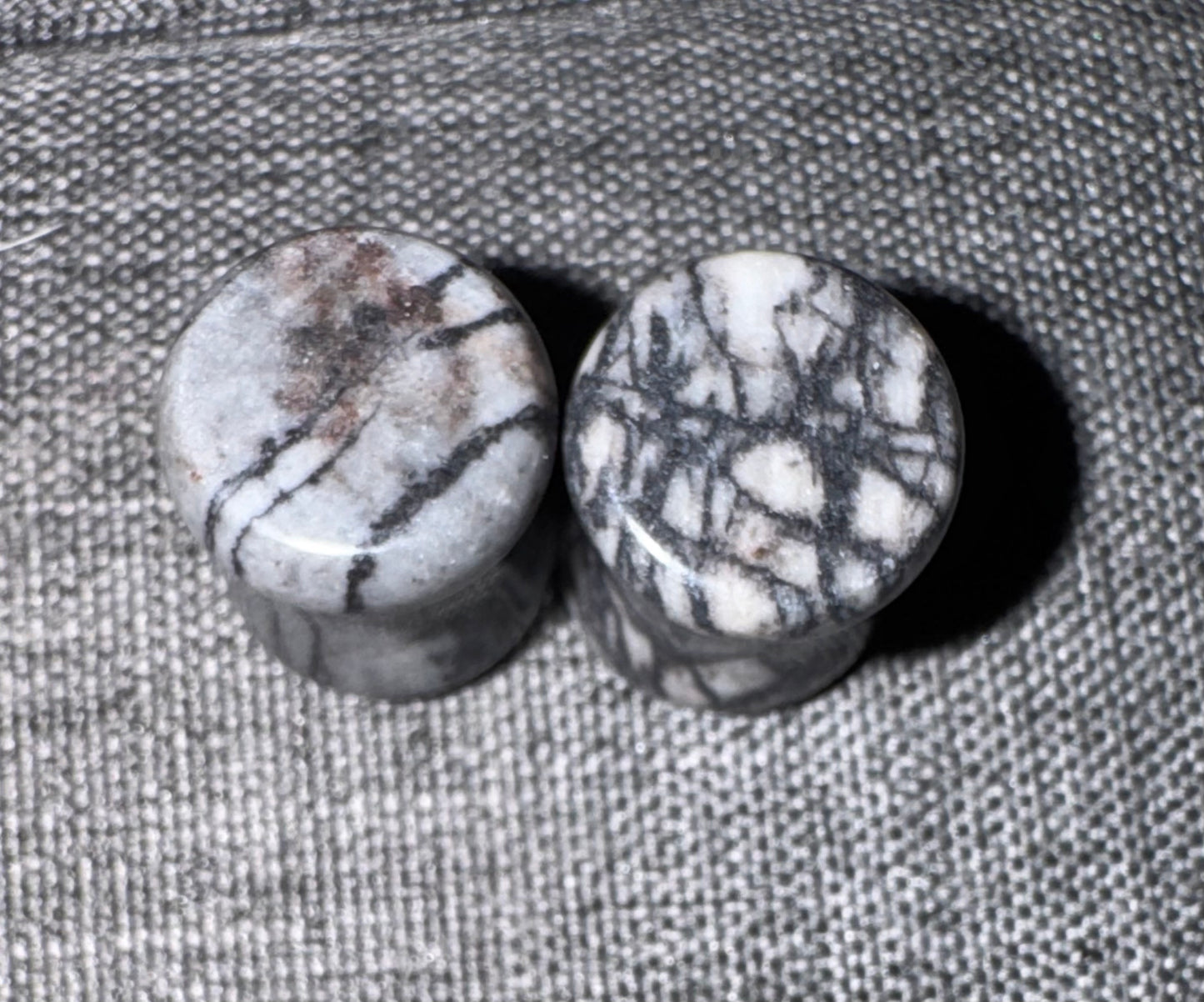 Two stone ear gauges on a textured fabric background