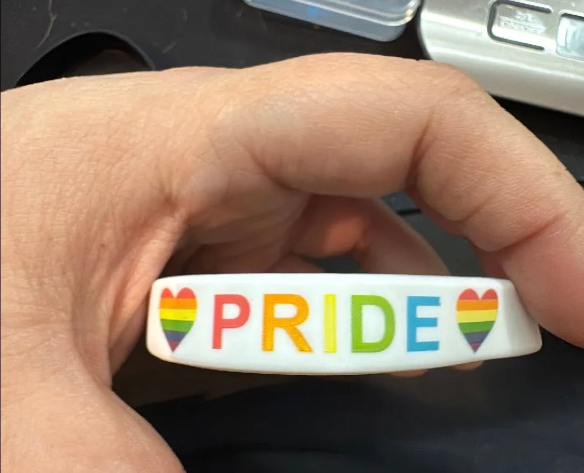 Pride wristband with rainbow hearts and letters.