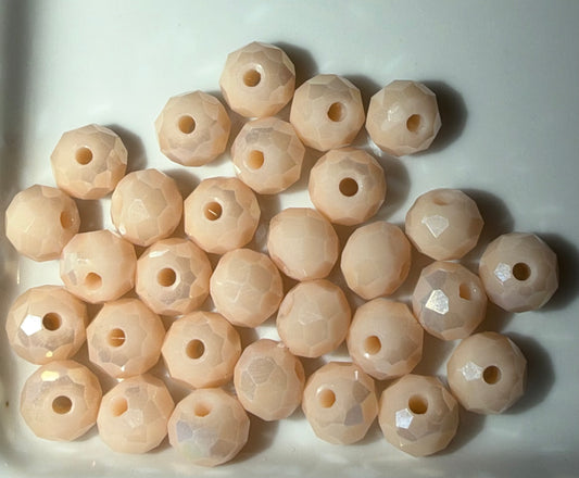 A group of faceted round beads in a pale peach-pink color, arranged on a white surface.