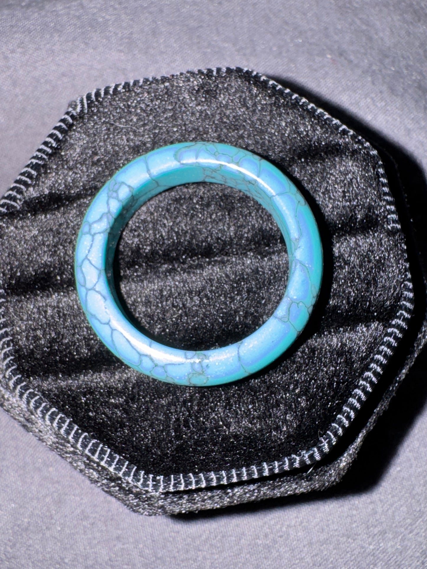Turquoise ring on a black textured stand