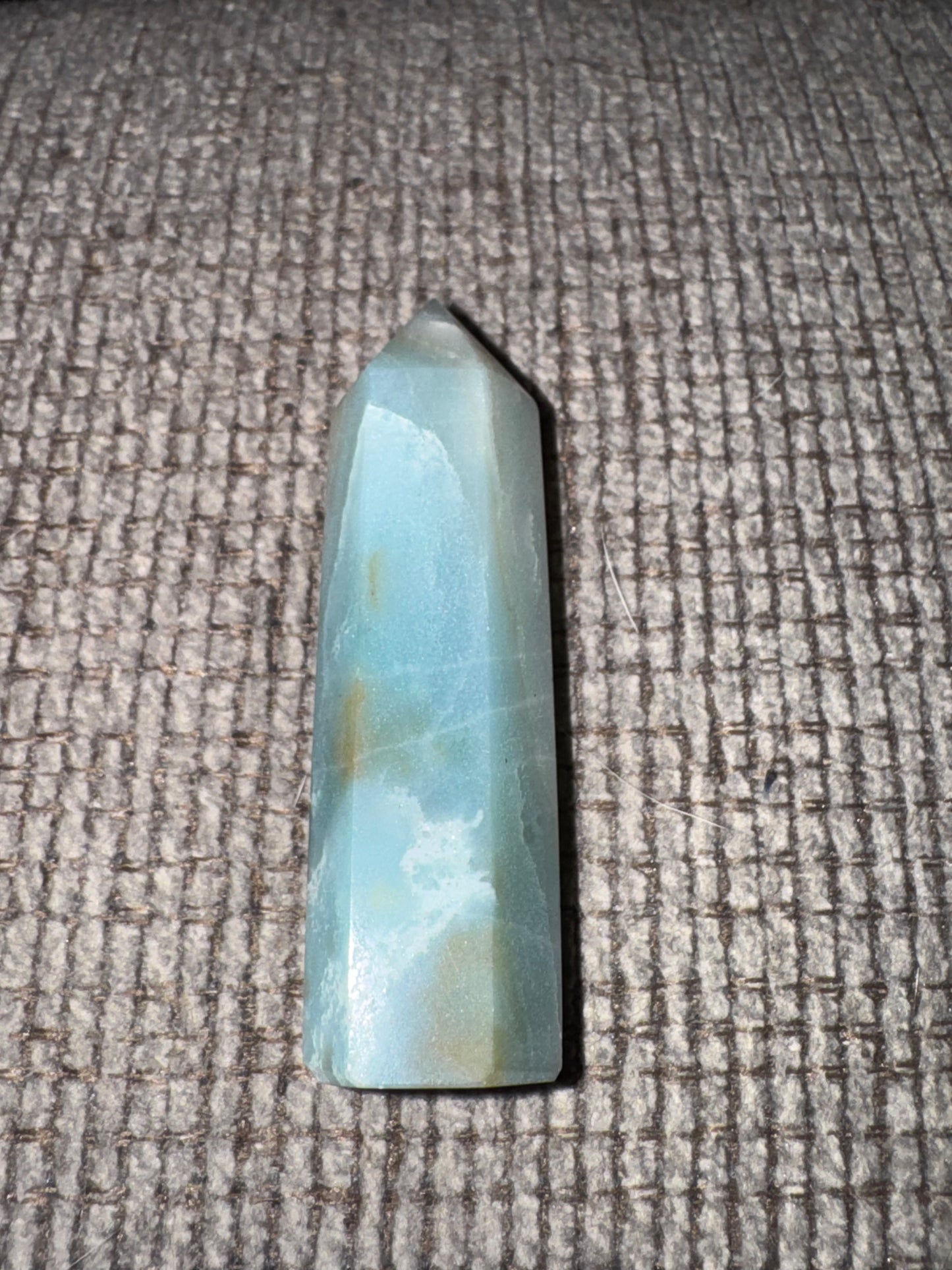 Blue-green crystal on a textured gray surface