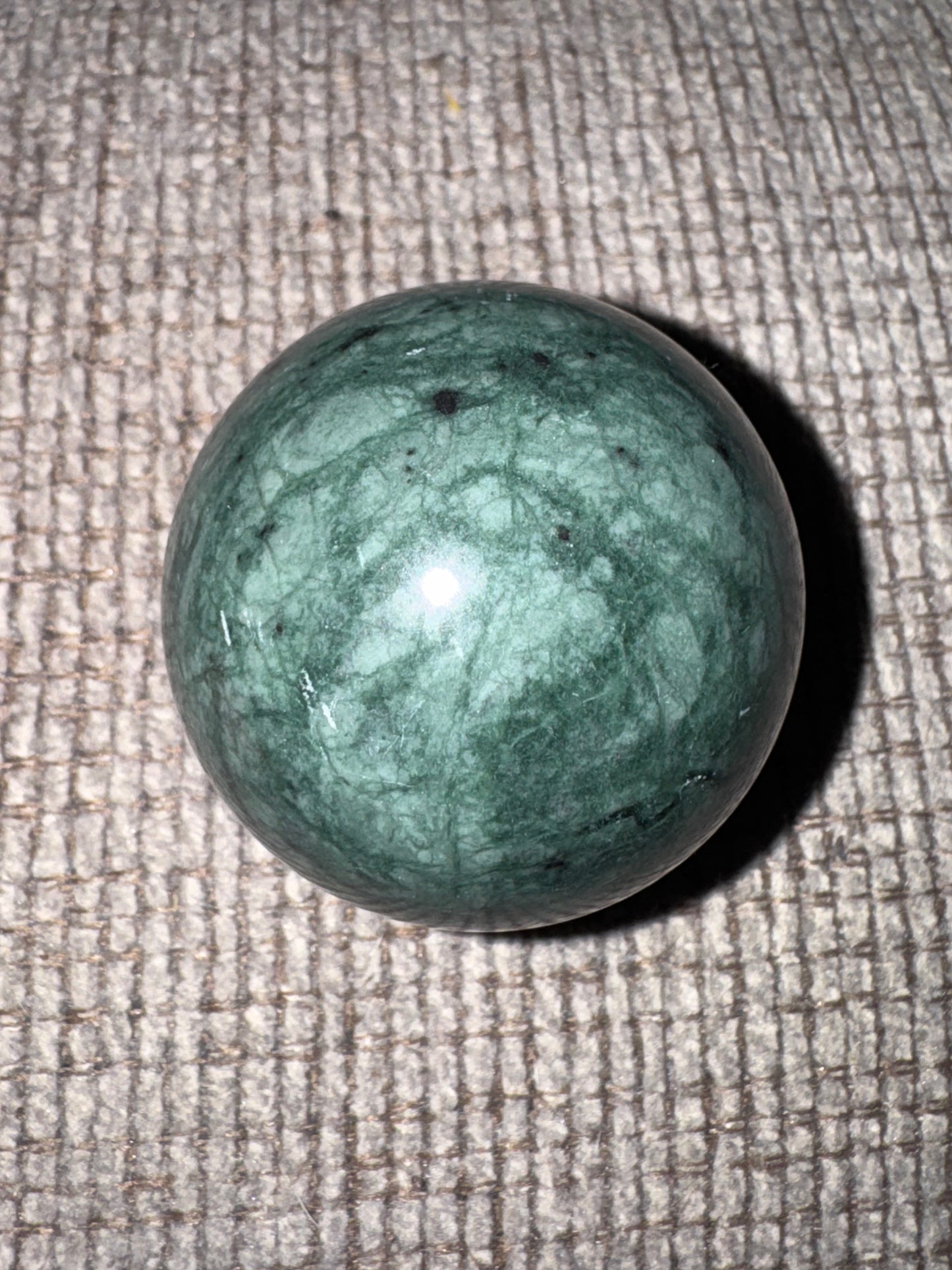 Jadite sphere on a textured beige surface