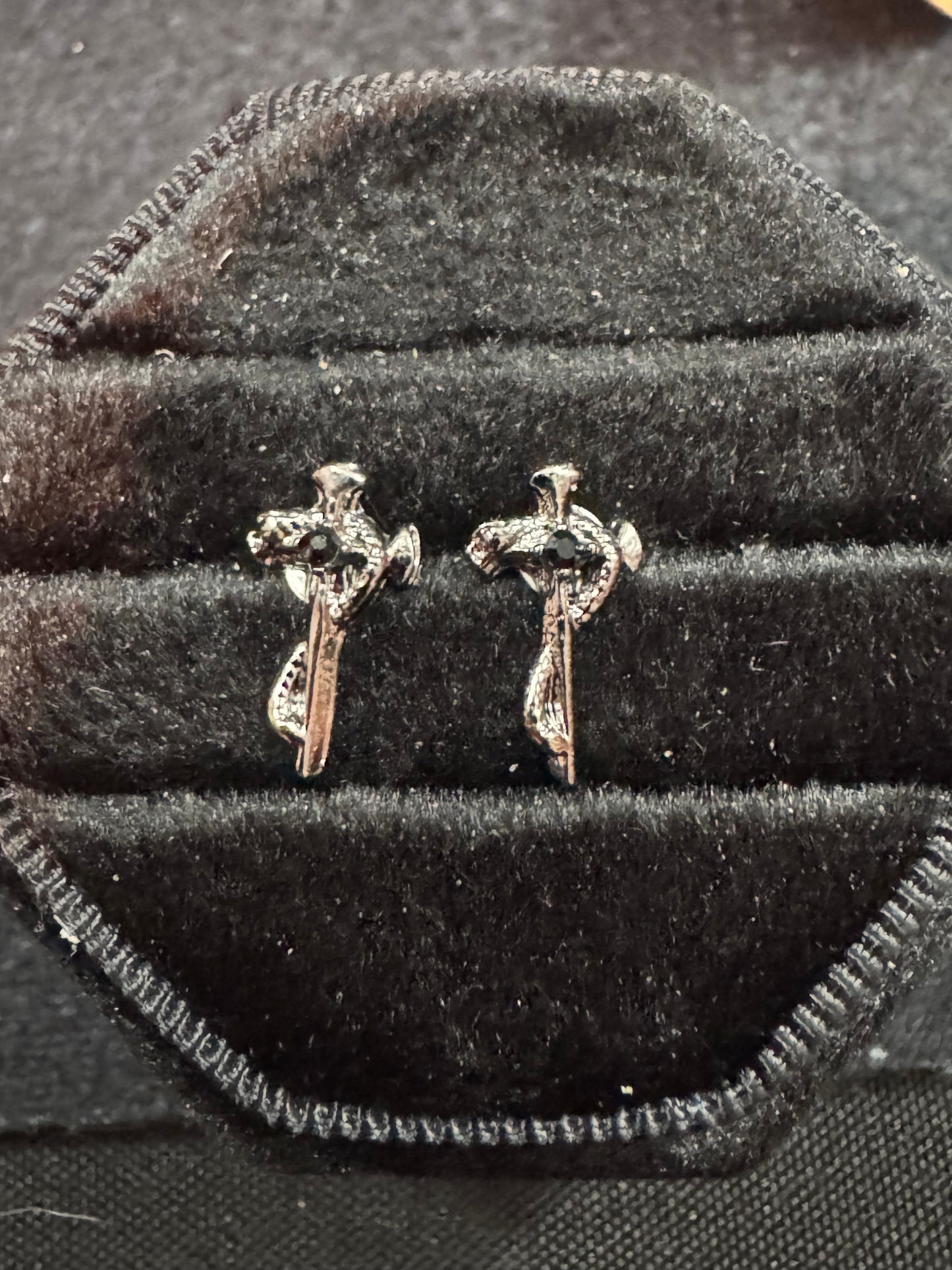 Pair of silver cross earrings on a black velvet surface