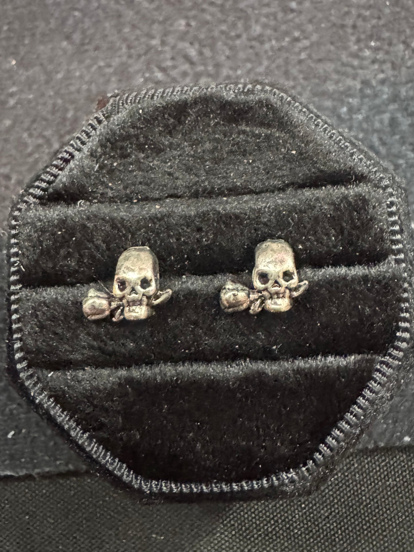 Skull-shaped earrings on a black velvet cushion
