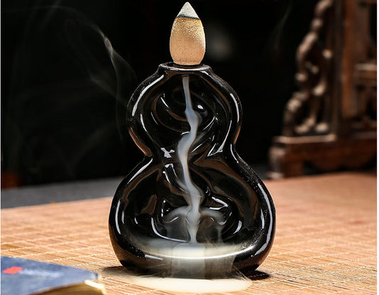 Black incense burner with smoke on a wooden surface