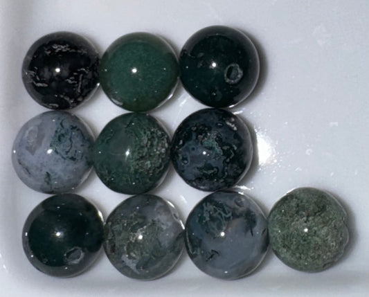 Nine polished oval gemstone beads in various shades of green, gray, and black with natural marbled patterns, arranged in a 3x3 grid on a white background.