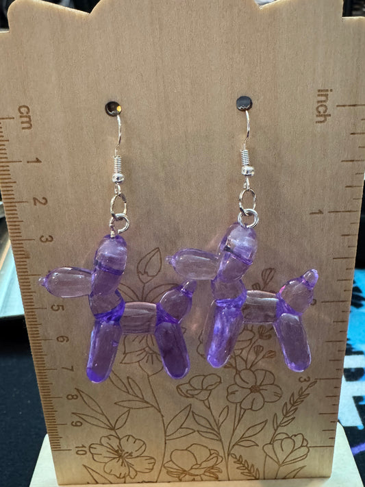 Purple ballon dog earrings on a wooden surface with a ruler for scale.