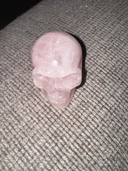 Pink crystal skull on a textured gray surface