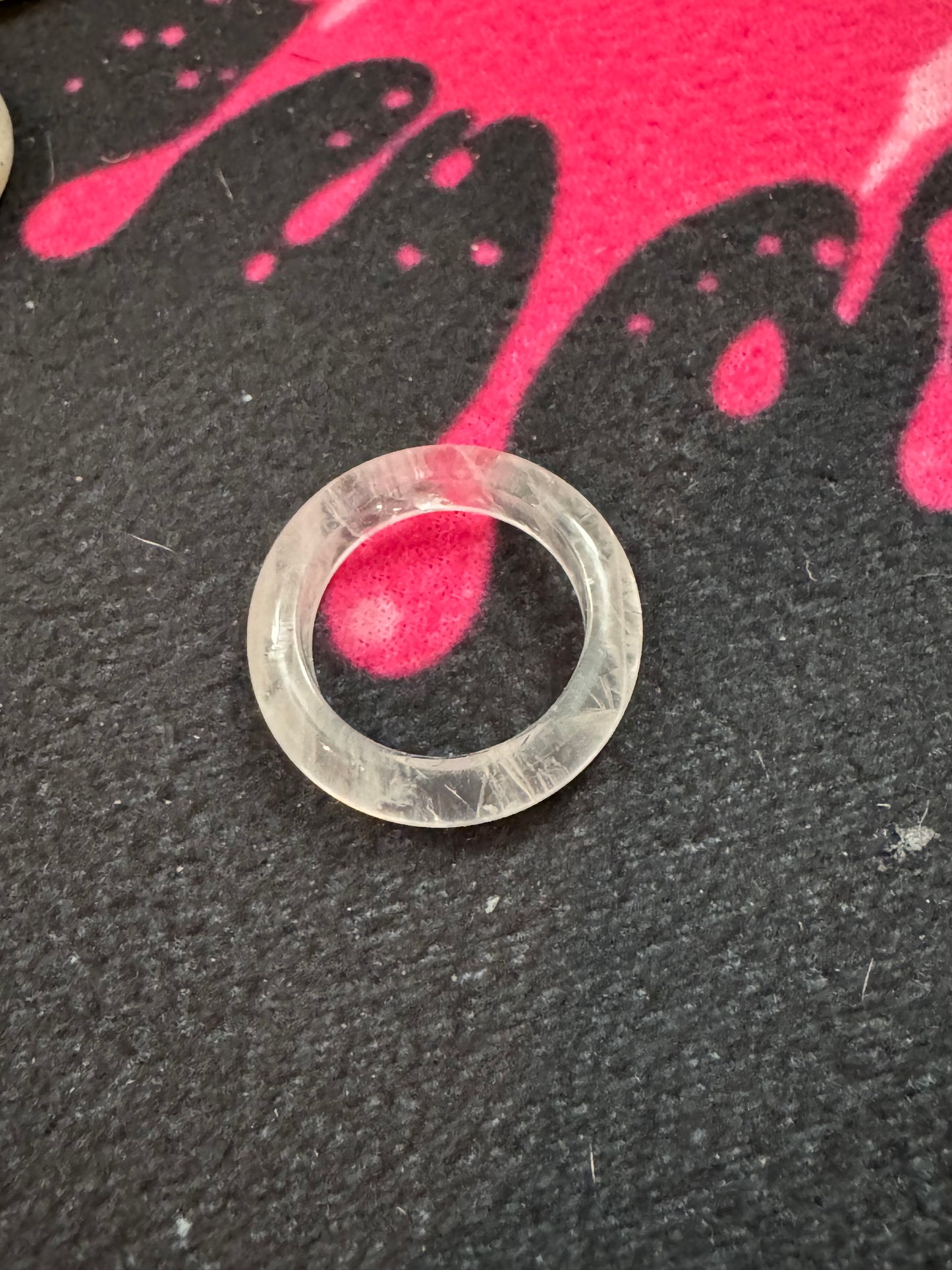 Clear Quartz Ring on a textured black surface with pink and black abstract design