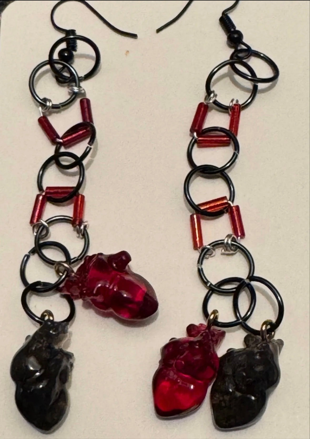 Pair of earrings with black and red heart-shaped beads on a white background