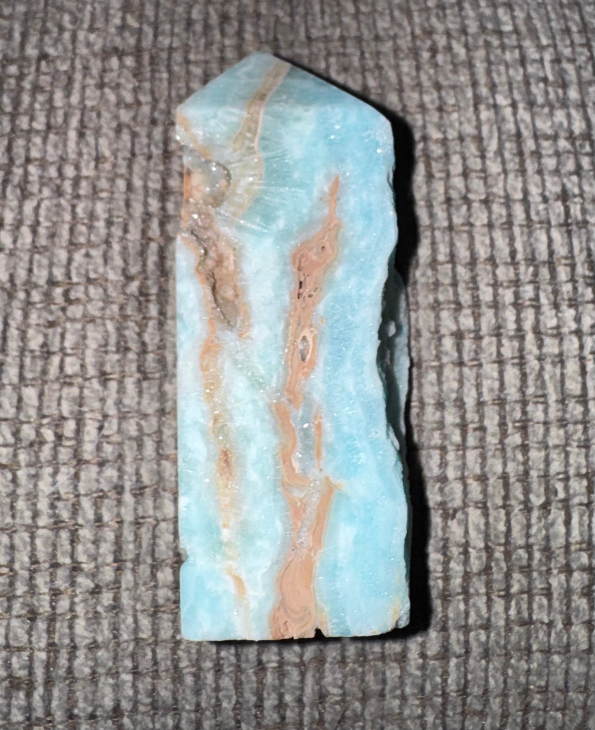 Crystal or mineral sample with blue and beige coloration on a textured surface