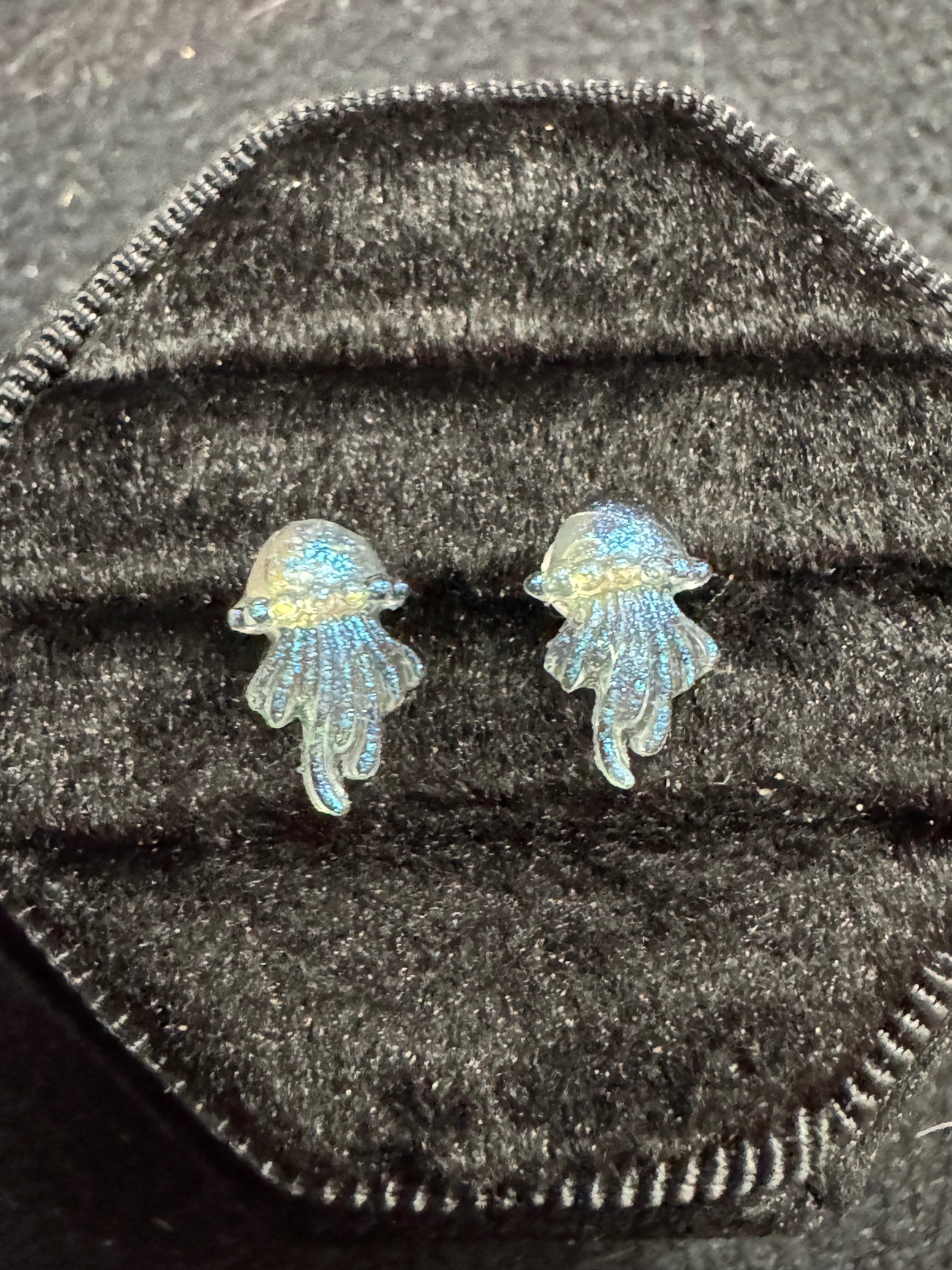 Pair of fish-shaped earrings on a textured black surface