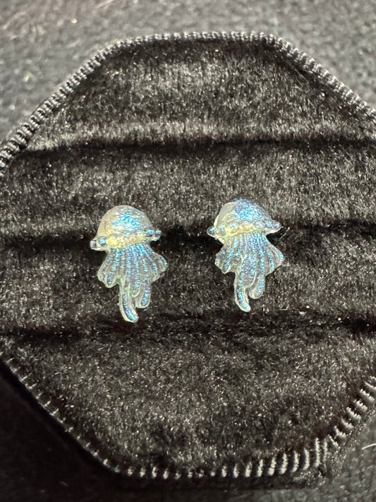 Pair of fish-shaped earrings on a textured black surface