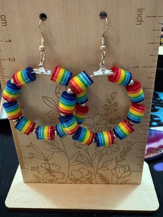 Rainbow beaded hoop earrings on a wooden surface with a ruler for scale.