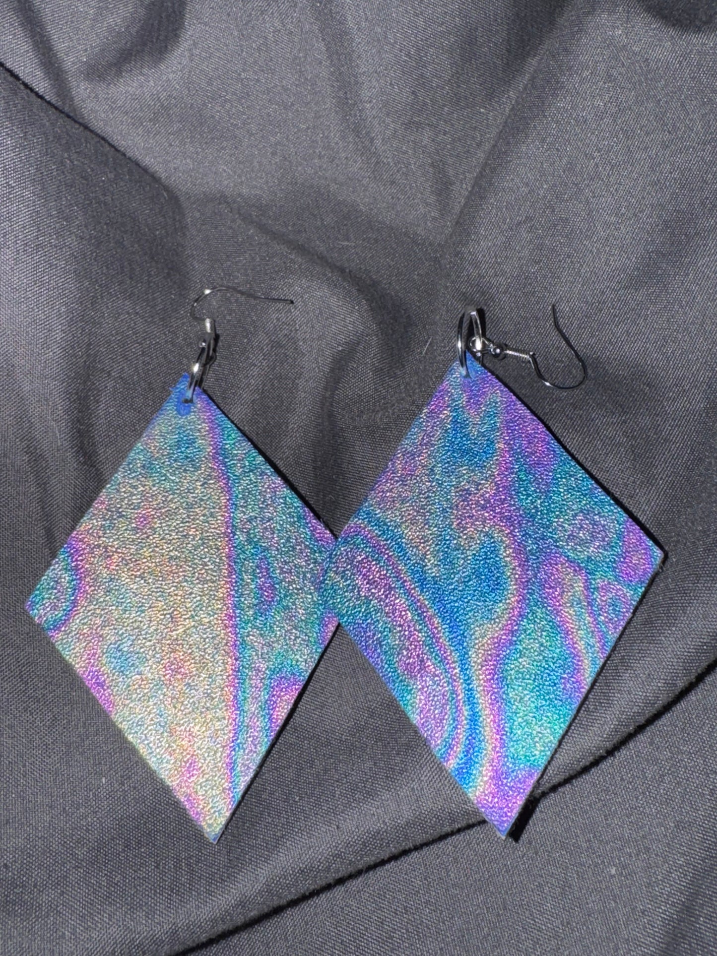 Holographic square earrings on a gray fabric background