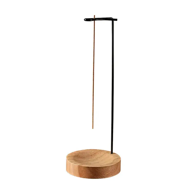 Modern incense holder with wooden base and black metal stand on a white background
