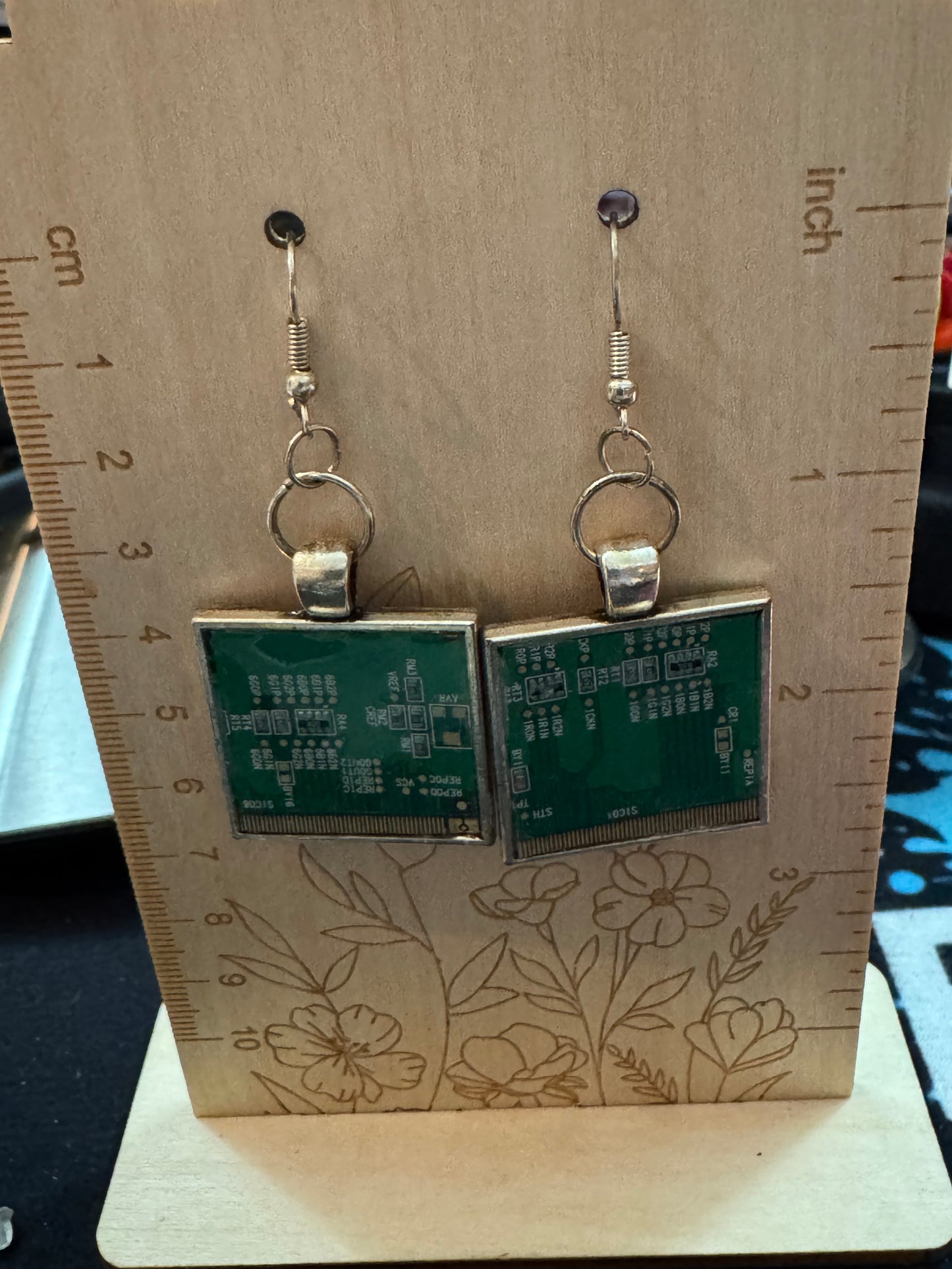 Circuit board earrings on a wooden board with a ruler for scale.