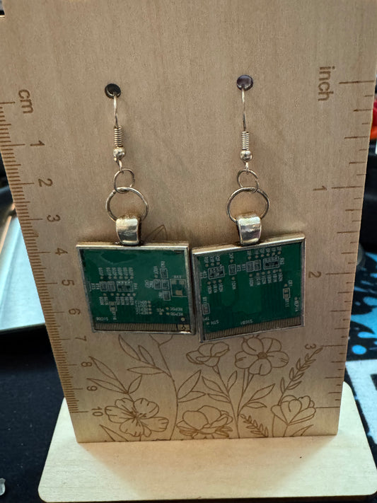 Circuit board earrings on a wooden board with a ruler for scale.