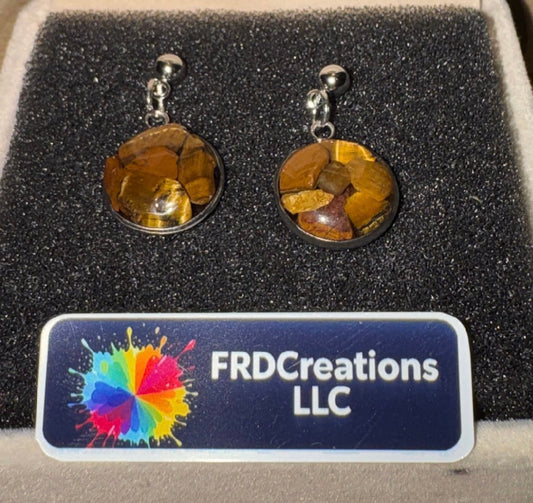 Pair of tiger eye stone earrings on a black cushion with FRDCreations LLC label.