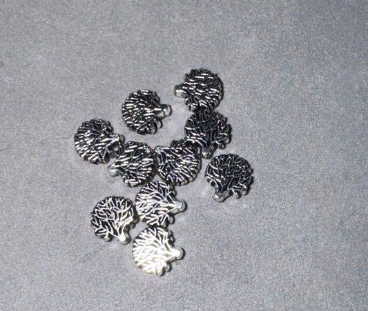A group of small metallic jewelry charms shaped like hedgehogs, displayed on a textured gray surface.