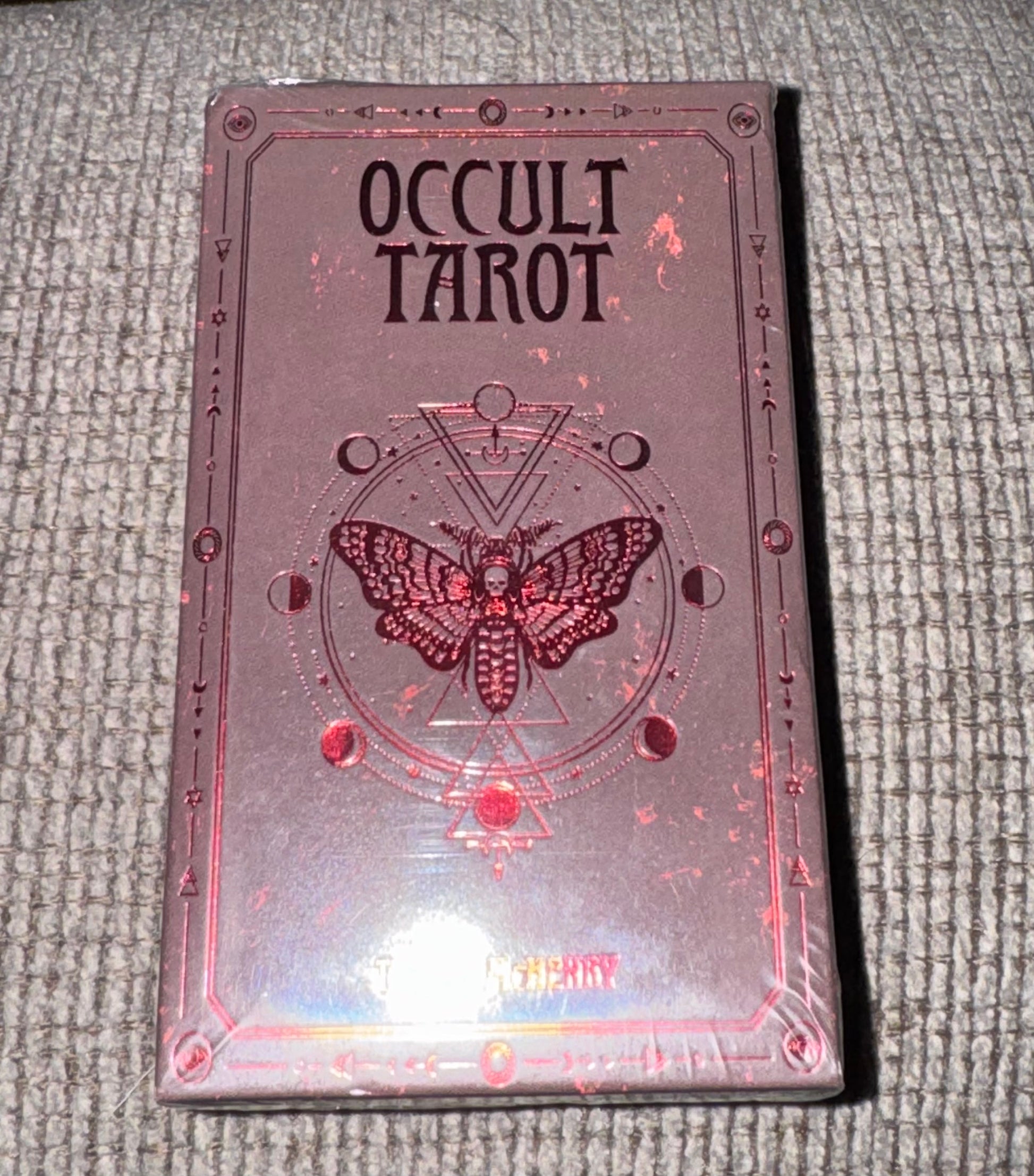 Occult Tarot card deck with a butterfly design on a textured surface