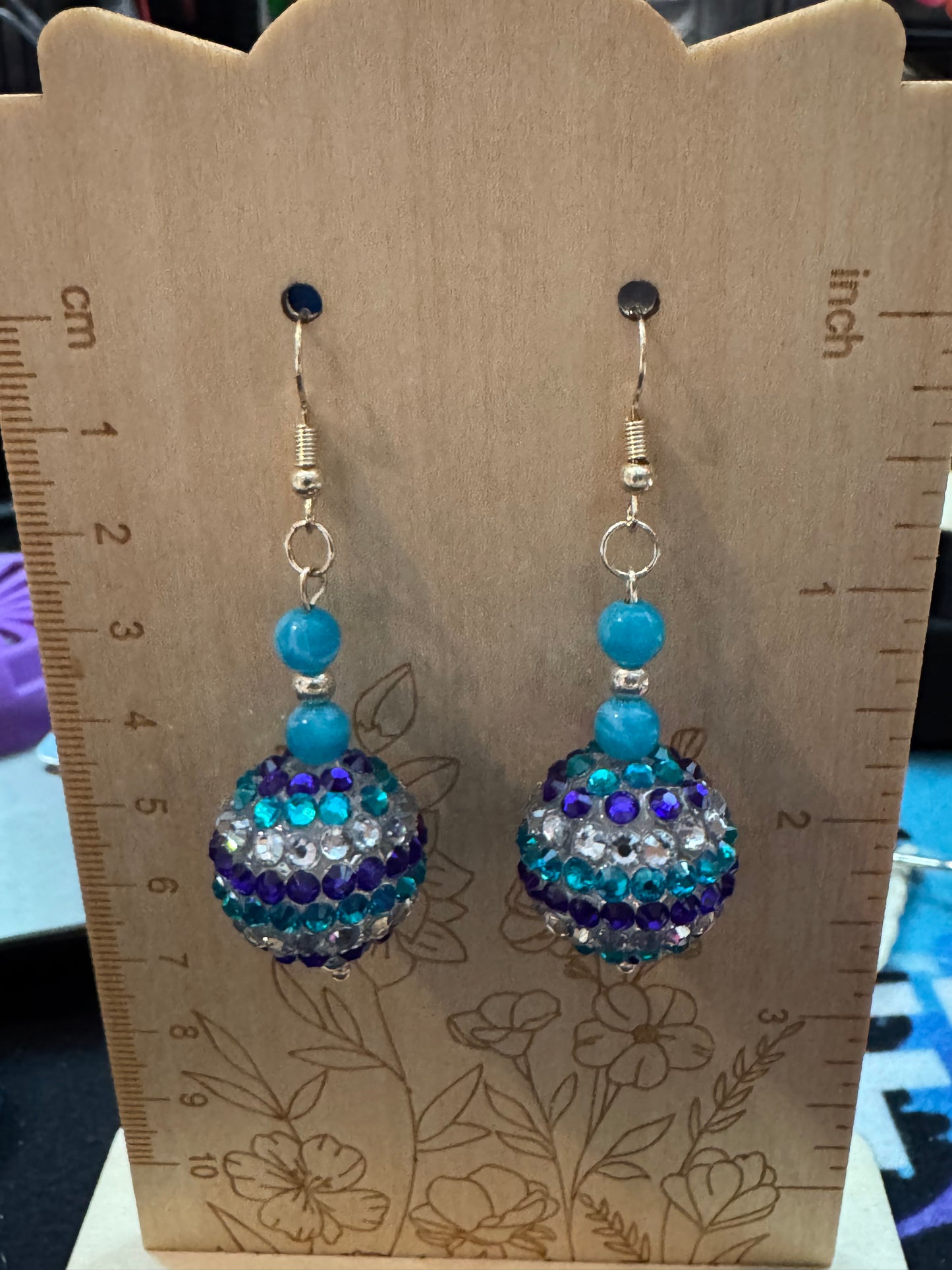 Pair of beaded earrings on a wooden display card with measurements.