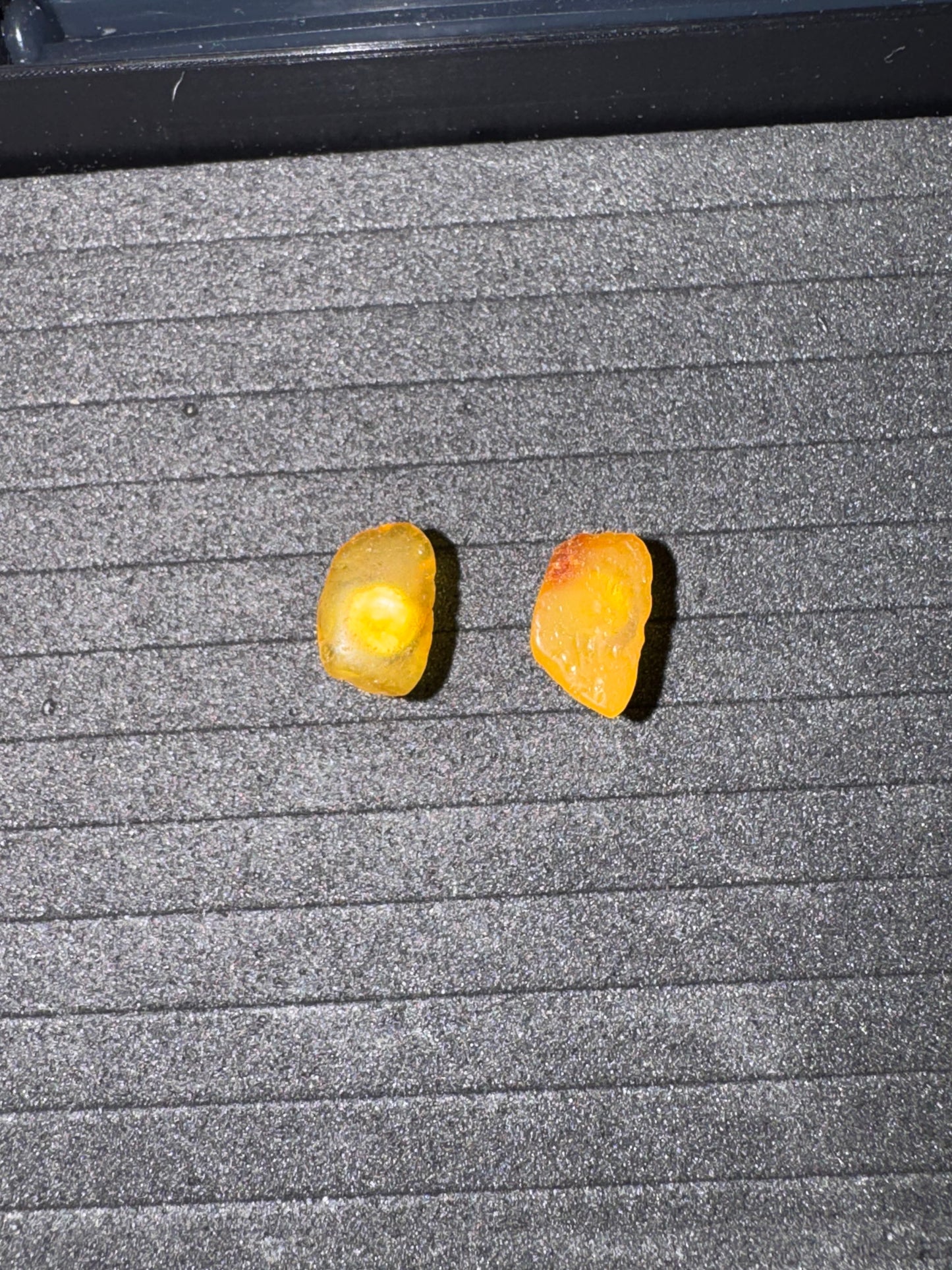 Two Amber earrings on a textured gray surface
