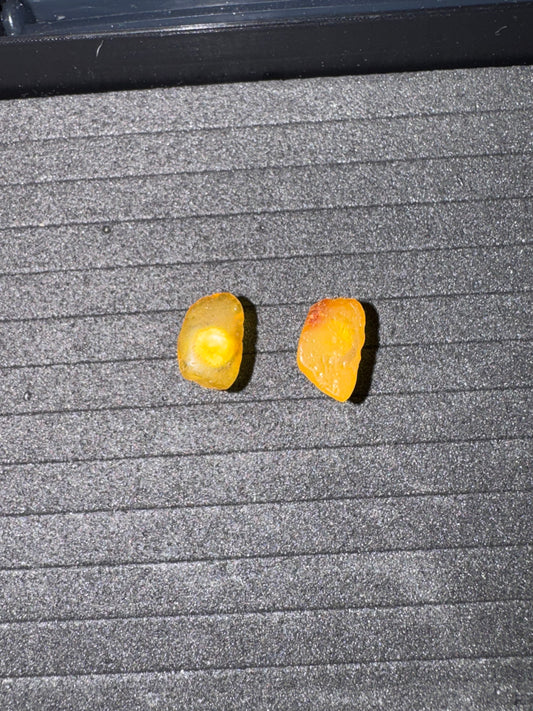 Two Amber earrings on a textured gray surface