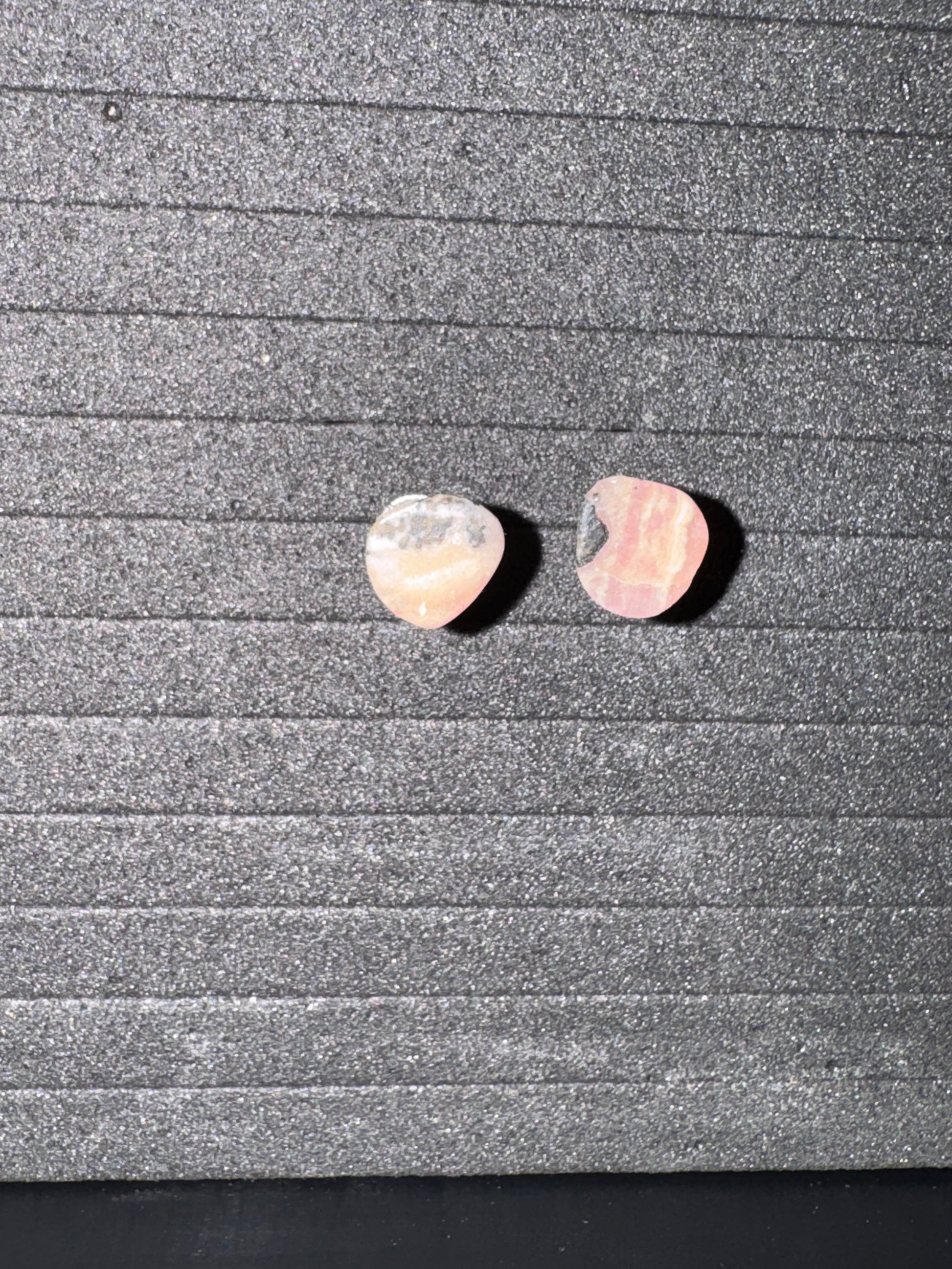 Two pink heart-shaped stones on a textured gray surface