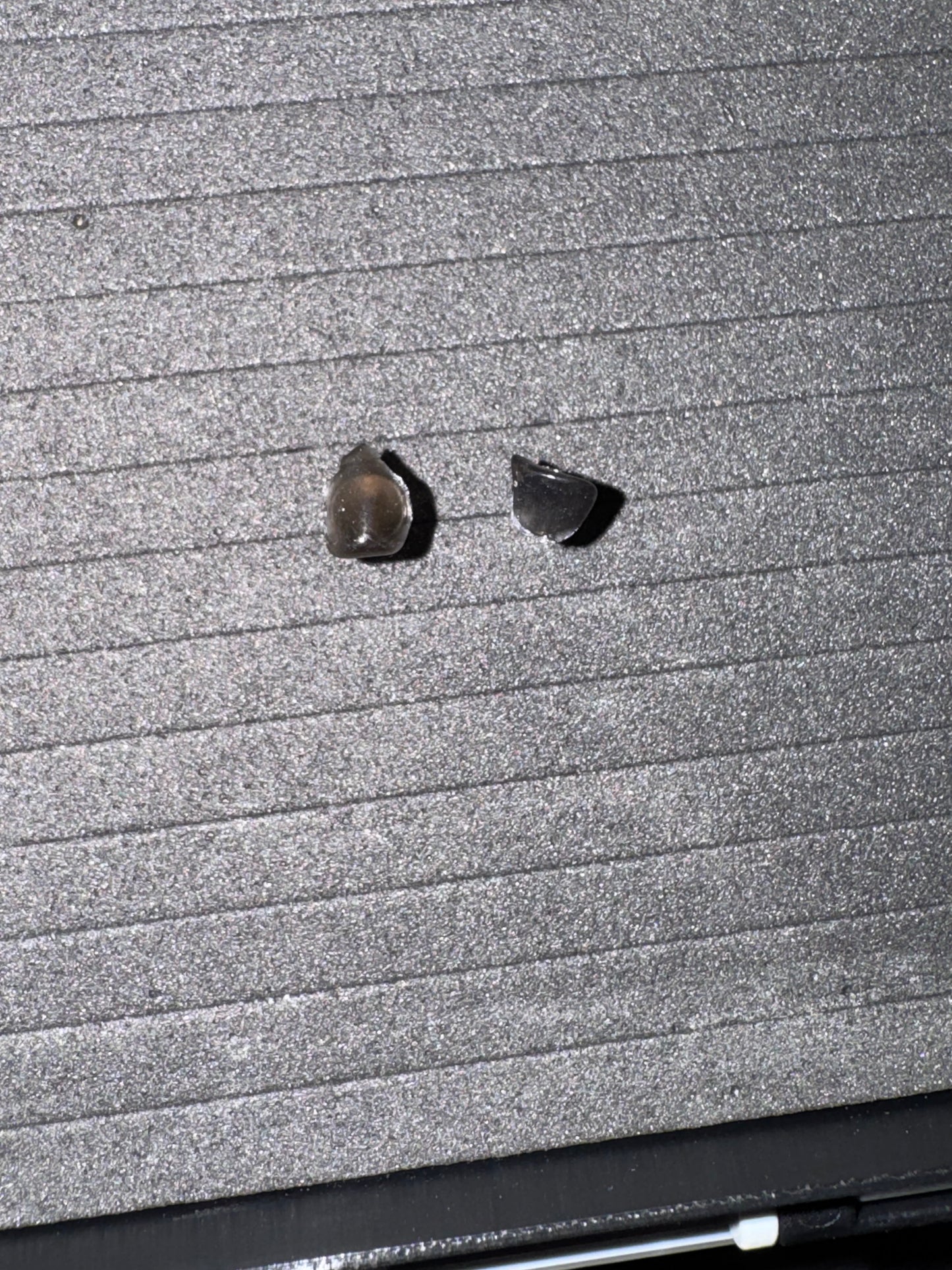 Two small earrings on a textured surface