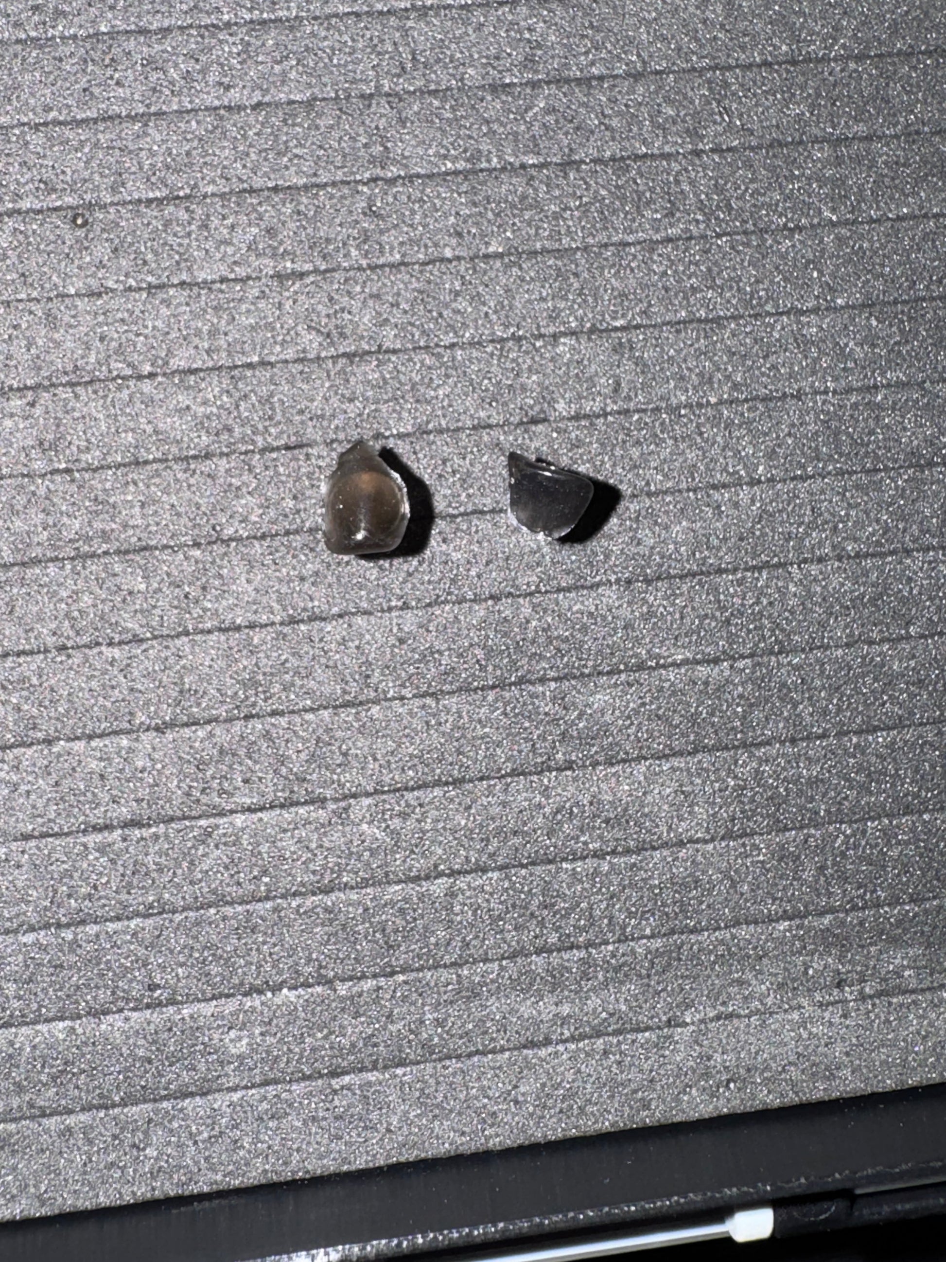 Two small earrings on a textured surface