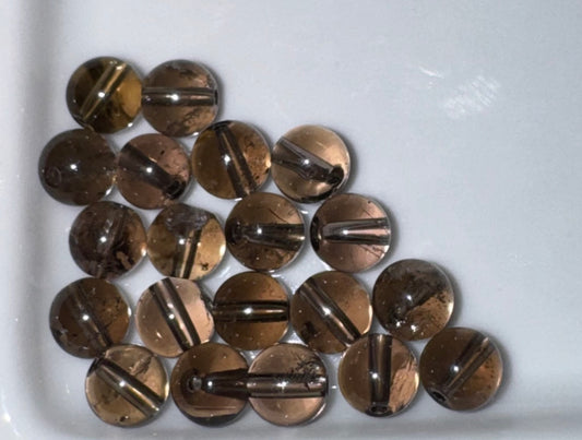 A group of round, polished brown smoky quartz gemstone beads with a central hole, arranged on a white surface.