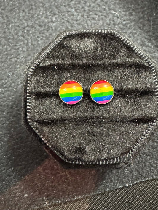Rainbow flag earrings on a gray fabric background