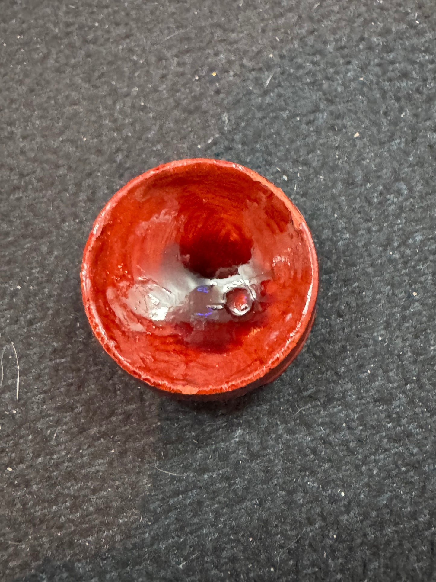 Small red ceramic object on a dark gray background
