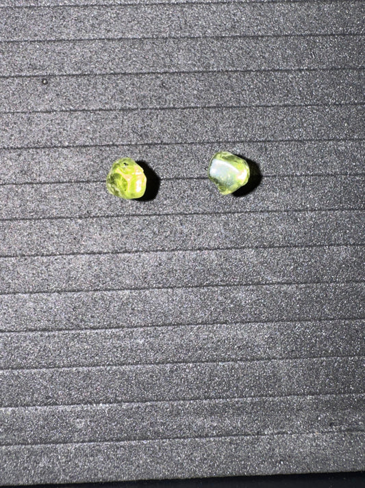 Two green earrings on a textured gray surface
